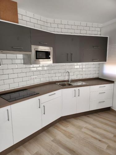 a kitchen with white cabinets and a sink and a microwave at Apartamentos Doña Emilia in Adeje