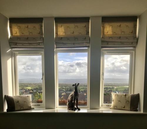 una ventana con una estatua de un perro sentada en un alféizar de la ventana en The Dog Inn en Longridge