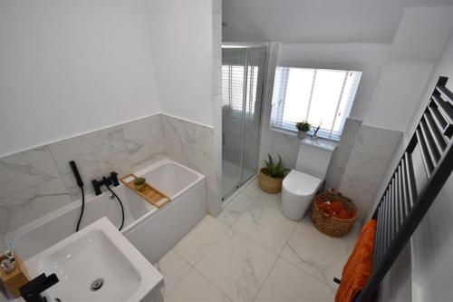 a white bathroom with a sink and a bath tub at 2 bedroom house in Hoylake - Golf Open in Hoylake