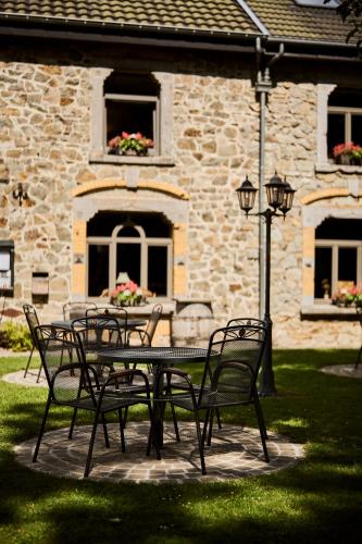 a table and chairs in front of a stone building at La Métairie Hôtel-Restaurant in Trois-Ponts