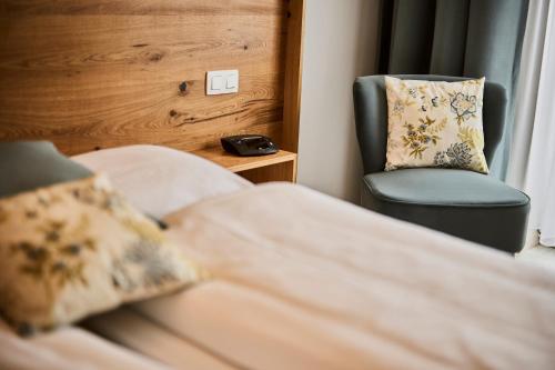 a bedroom with a chair and a bed and a clock at La Métairie Hôtel-Restaurant in Trois-Ponts