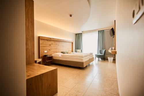 a bedroom with a bed and a chair and a window at Logis Hotel La Métairie & Son Auberge in Trois-Ponts