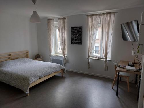 1 dormitorio con 1 cama, escritorio y 2 ventanas en Studio tout confort, en Corny-sur-Moselle