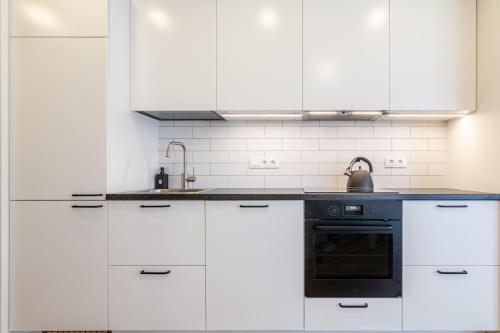 a kitchen with white cabinets and a black oven at Elija Swan-Toy Apartments in Šventoji