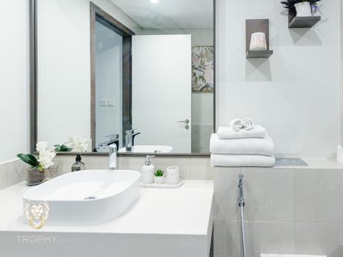 a white bathroom with a sink and a mirror at Luxury 1BR Apt with Unobstructed Dubai Frame View in Dubai
