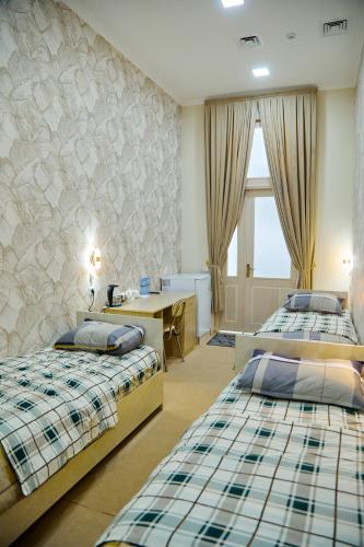 a hotel room with two beds and a desk and a desk at YUKSALISH HOSTEL in Samarkand