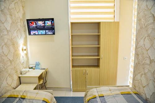 a room with two beds and a desk and a tv at YUKSALISH HOSTEL in Samarkand