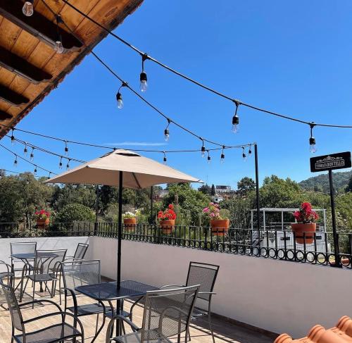 a patio with tables and chairs and an umbrella at Hotel Casa Francisca Mazamitla. in Mazamitla