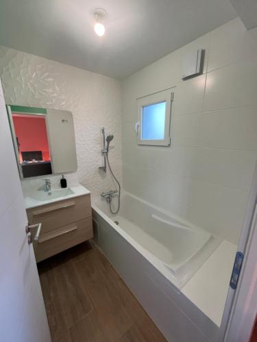 a white bathroom with a tub and a sink at SCI BSA Magnifique maison au calme in Les Essards-Taignevaux