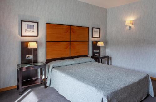 a bedroom with a large bed and two tables with lamps at Hotel Macià Real De La Alhambra in Granada