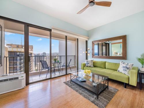 a living room with a green couch and a balcony at Penthouse With Fabulous Ocean View Near Waikiki Beach in Honolulu