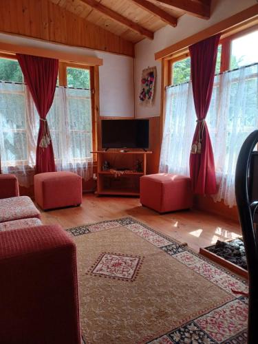 a living room with red furniture and windows at Cabaña del Volcán in Licán Ray