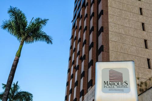 a sign in front of a building with a palm tree at Marques Plaza Hotel in Pouso Alegre