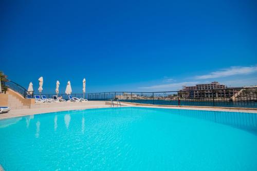 a large blue swimming pool next to a beach at Marina Hotel Corinthia Beach Resort Malta in St. Julianʼs