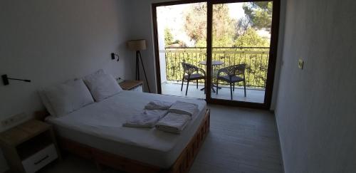 a bedroom with a bed and a balcony with a table at Lindos Pension in Dalyan