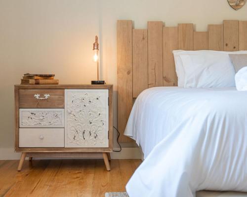 a bedroom with a bed and a night stand with a white bedspread at Quinta de Carcavelos Natures Home in Amarante