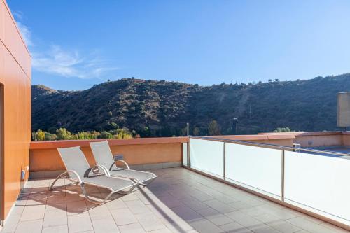 two chairs on a balcony with a view of a mountain at Hotel Macià Real De La Alhambra in Granada