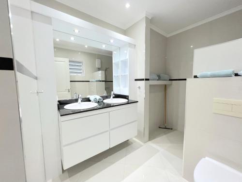 Baño blanco con 2 lavabos y espejo en Apartment in luxury villa with private pool, en Willemstad