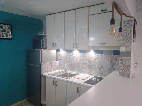 Una cocina con gabinetes blancos y un fregadero. en Santa Clara, en Almería