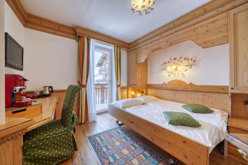 a bedroom with a bed and a desk and a chair at La Torretta in Passo del Tonale