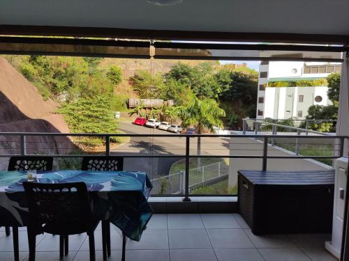 a balcony with a table and a view of a street at Elégant F3 à la Villa Stencer, Papeete, calme climatisé et spacieux in Papeete