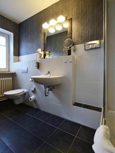 a bathroom with a sink and a toilet and a mirror at Comfort Hotel tom Kyle in Kiel