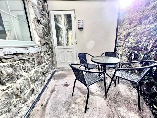 a patio with three chairs and a table and a window at Trevose in Wrexham