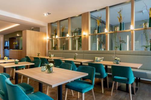 a restaurant with wooden tables and blue chairs at Altstadthotel Arch in Regensburg