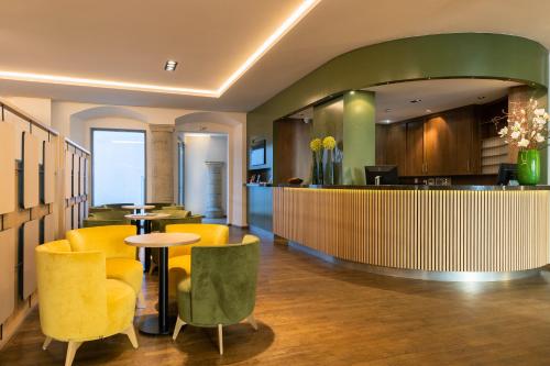 a restaurant with yellow and green chairs and a bar at Altstadthotel Arch in Regensburg