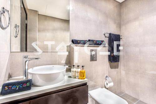 een badkamer met een wastafel, een toilet en een spiegel bij Staycae Holiday Homes - Merano in Dubai