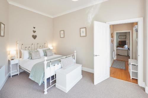 a white bedroom with a bed and a hallway at Host & Stay - Rose Cottage in Aldbrough