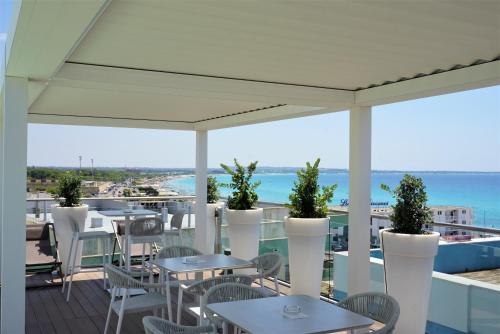 un patio con tavoli, sedie e vista sull'oceano di M&F Hotel a Gallipoli
