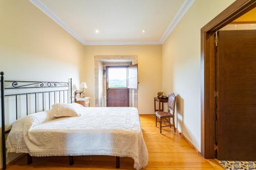 a bedroom with a bed and a table and a window at Casa Rural Pazo San Damian in Amoeiro