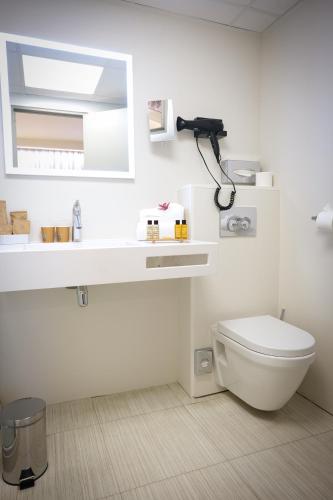 a white bathroom with a toilet and a mirror at Mercure Perpignan Centre in Perpignan