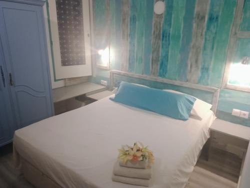 a bedroom with a white bed with a blue pillow and towels at Casa Violette in Almería