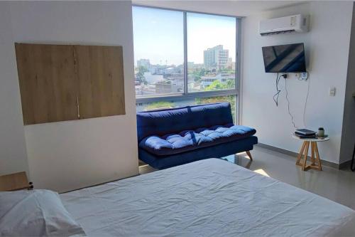 1 dormitorio con sofá azul y ventana grande en Estudio para 3, Norte de Barranquilla, en Barranquilla