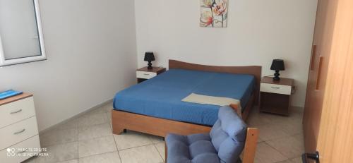 1 dormitorio pequeño con 1 cama y 1 silla azul en Casa Domenica, en Torre Lapillo