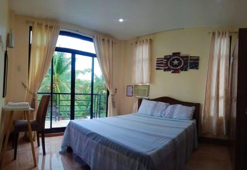 1 dormitorio con cama y ventana grande en DJL Summer House - Bantayan Island, en Patao