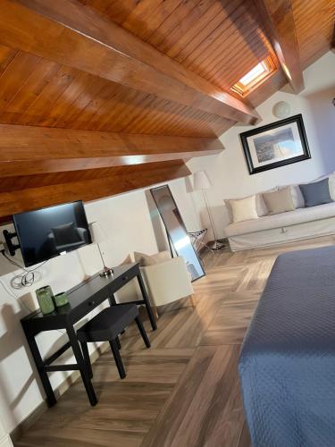 Habitación con cama, escritorio y sofá. en Palazzo Candida B&B en Gerace