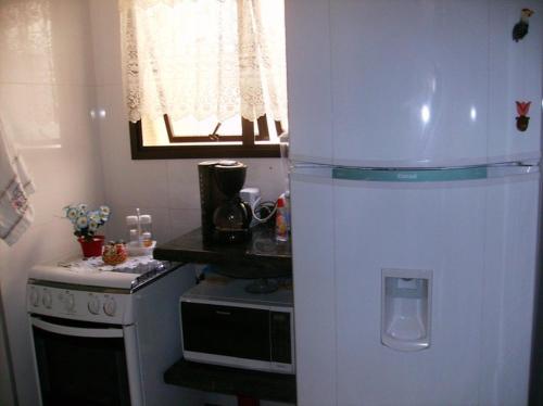 Il comprend une cuisine équipée d'un réfrigérateur blanc et d'une cuisinière. dans l'établissement Confortável Apto.Com Piscina para 8 pessoas-Ubatuba-Enseada, à Ubatuba