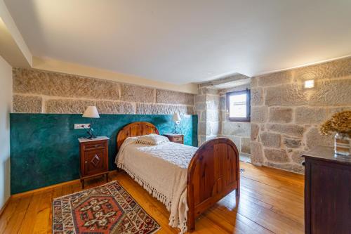a bedroom with a bed and a stone wall at Casa Rural Pazo San Damian in Amoeiro