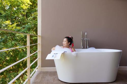 a woman sitting in a bath tub in a room with a window at Onhill Village in Pong Talong