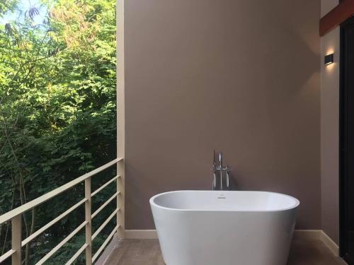 uma banheira branca num quarto com uma janela em Onhill Village em Pong Talong