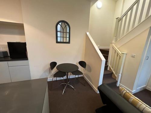 a table and chairs in a room with a staircase at Lovely One Bedroom Apartment in Rotherham