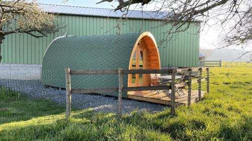 un edificio verde con una valla delante en Au pré des Alizés - insolite à la ferme des Alizés, en Vallon-sur-Gée