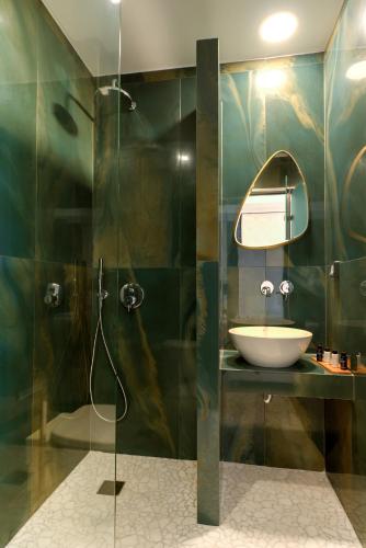 a bathroom with a sink and a shower with a mirror at Deluxe Suites Santorini in Fira