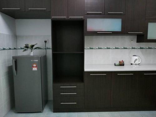 a kitchen with brown cabinets and a refrigerator at Sapporo Homestay in Skudai