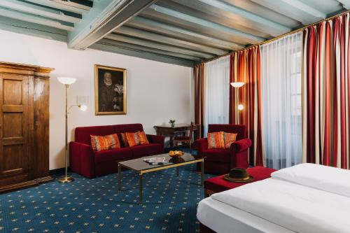 une chambre d'hôtel avec un lit et deux chaises rouges dans l'établissement Altstadthotel Arch, à Ratisbonne