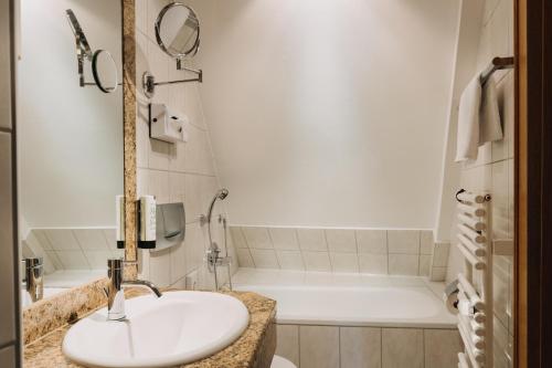 a bathroom with a sink and a bath tub at Altstadthotel Arch in Regensburg