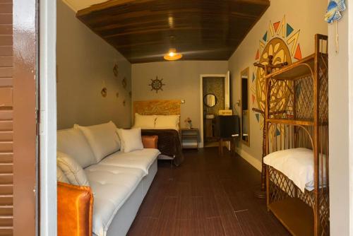 a living room with a white couch and a bed at Pousada Village Mel in Ilha do Mel